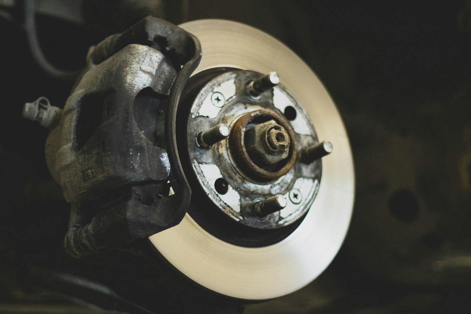 Brake caliper clamped over a disc brake rotor on a car with the wheel removed