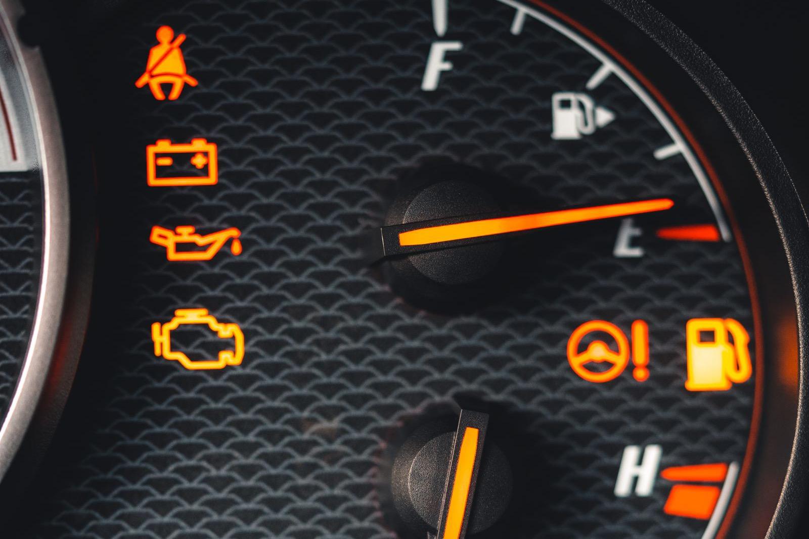 Amber check engine light lit on a car's instrument cluster next to the oil and battery warning lights