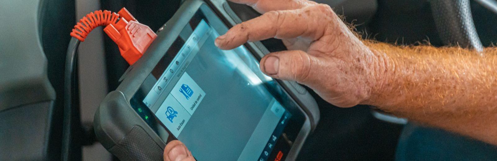 Technician using a professional OBD-II scan tool plugged into a car's diagnostic port
