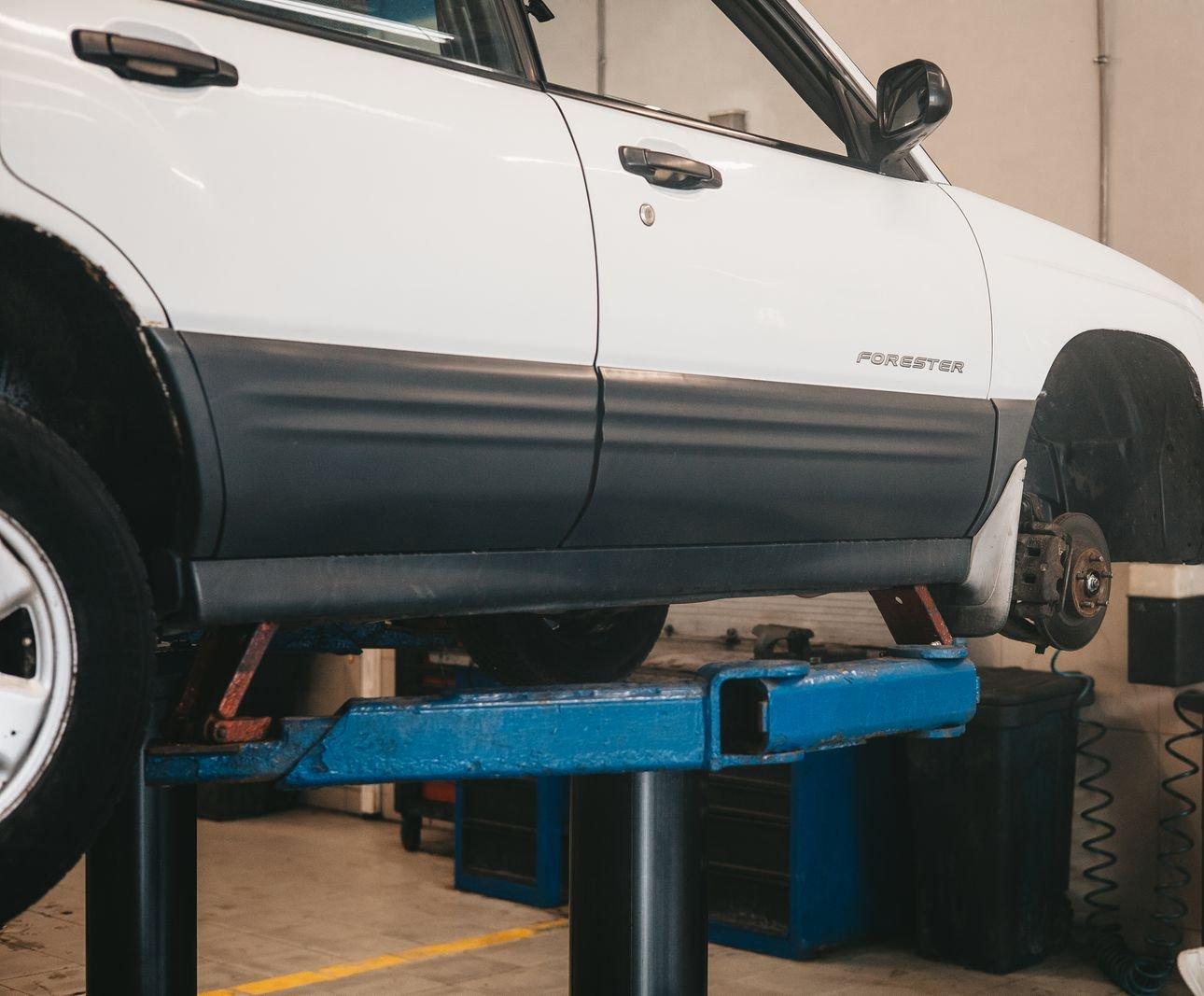 SUV raised on a lift with the front wheel off, showing the brake rotor and caliper