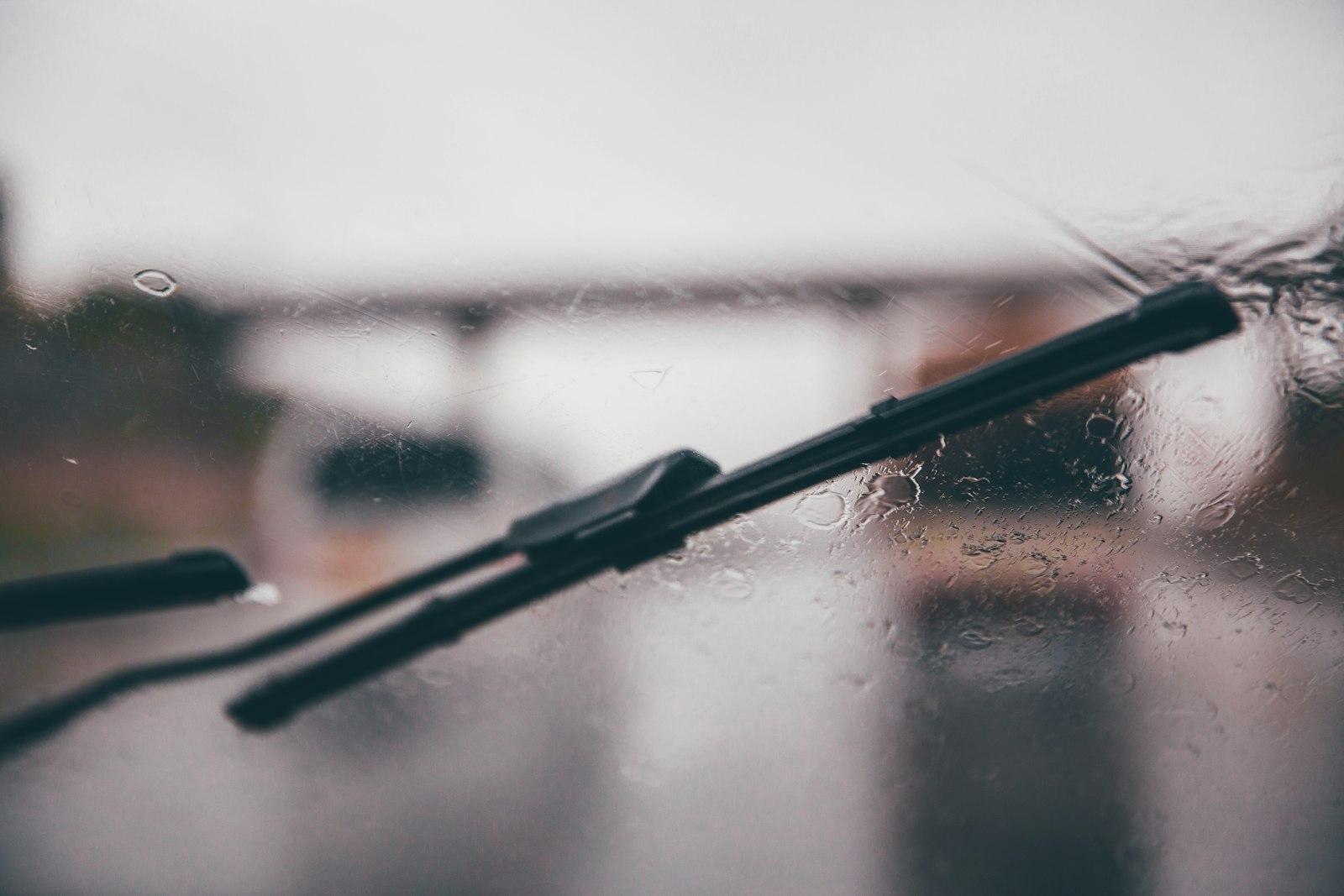Windshield wiper blade clearing rain from a car windshield